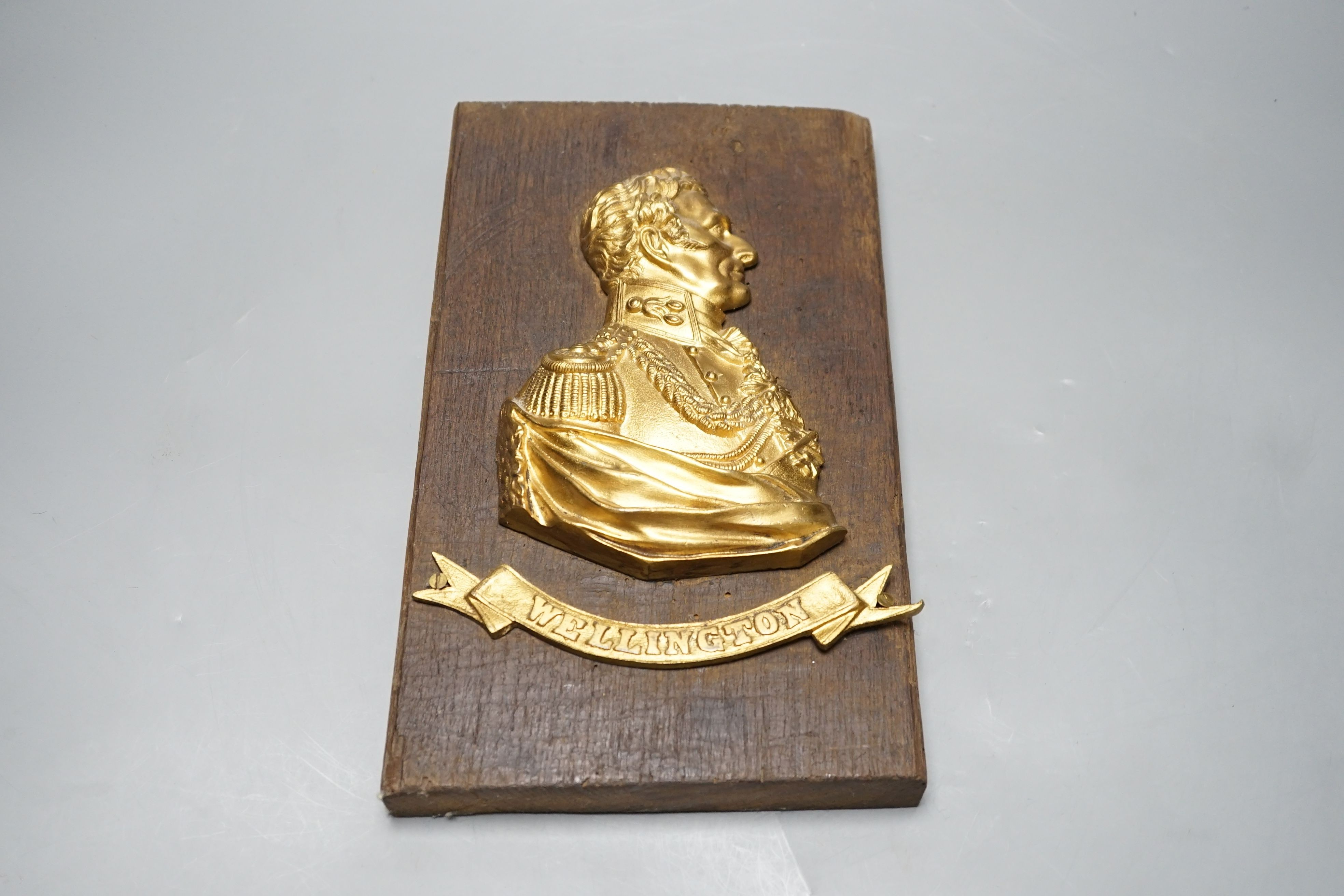 A gilt metal ‘Wellington’ plaque on wooden panel, 30 x 19cm